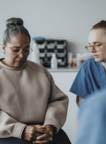 A distressed woman sitting next to a healthcare worker